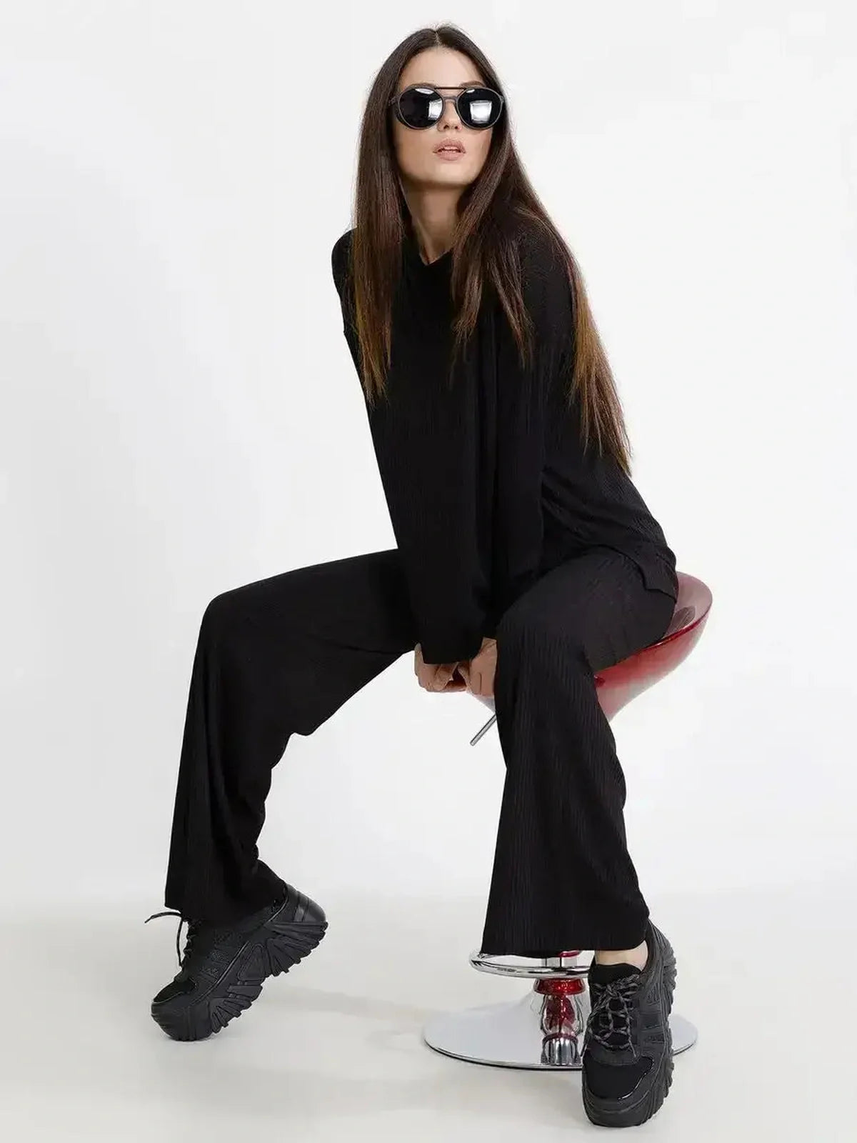 Model wearing the Jet Black Set, a ribbed two-piece outfit with relaxed fit, black sunglasses, and chunky black sneakers.