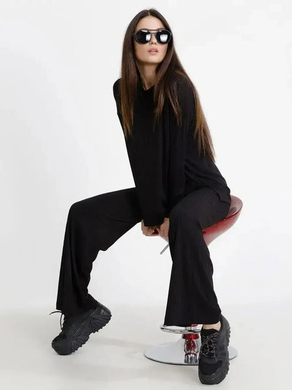 Model wearing the Jet Black Set, a ribbed two-piece outfit with relaxed fit, black sunglasses, and chunky black sneakers.