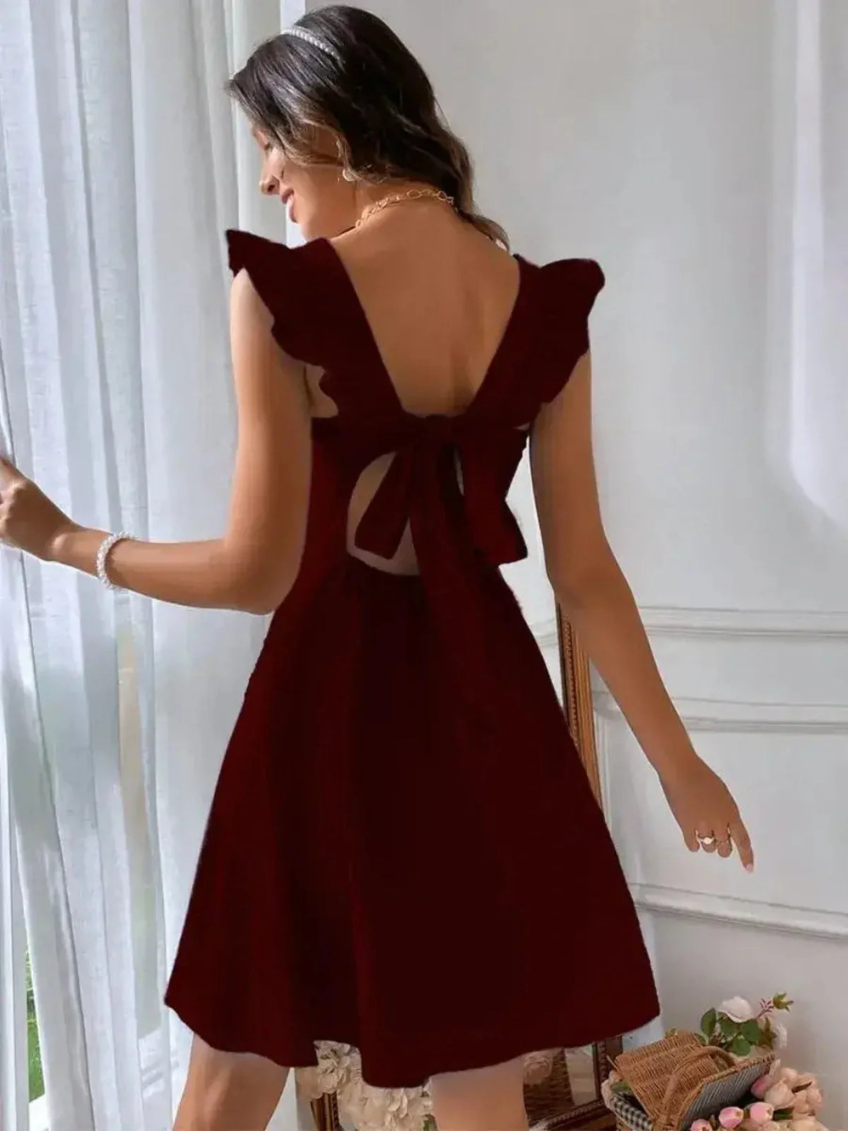 Back view of a captivating burgundy mini dress with flutter sleeves and a bow detail for women, perfect for summer events.