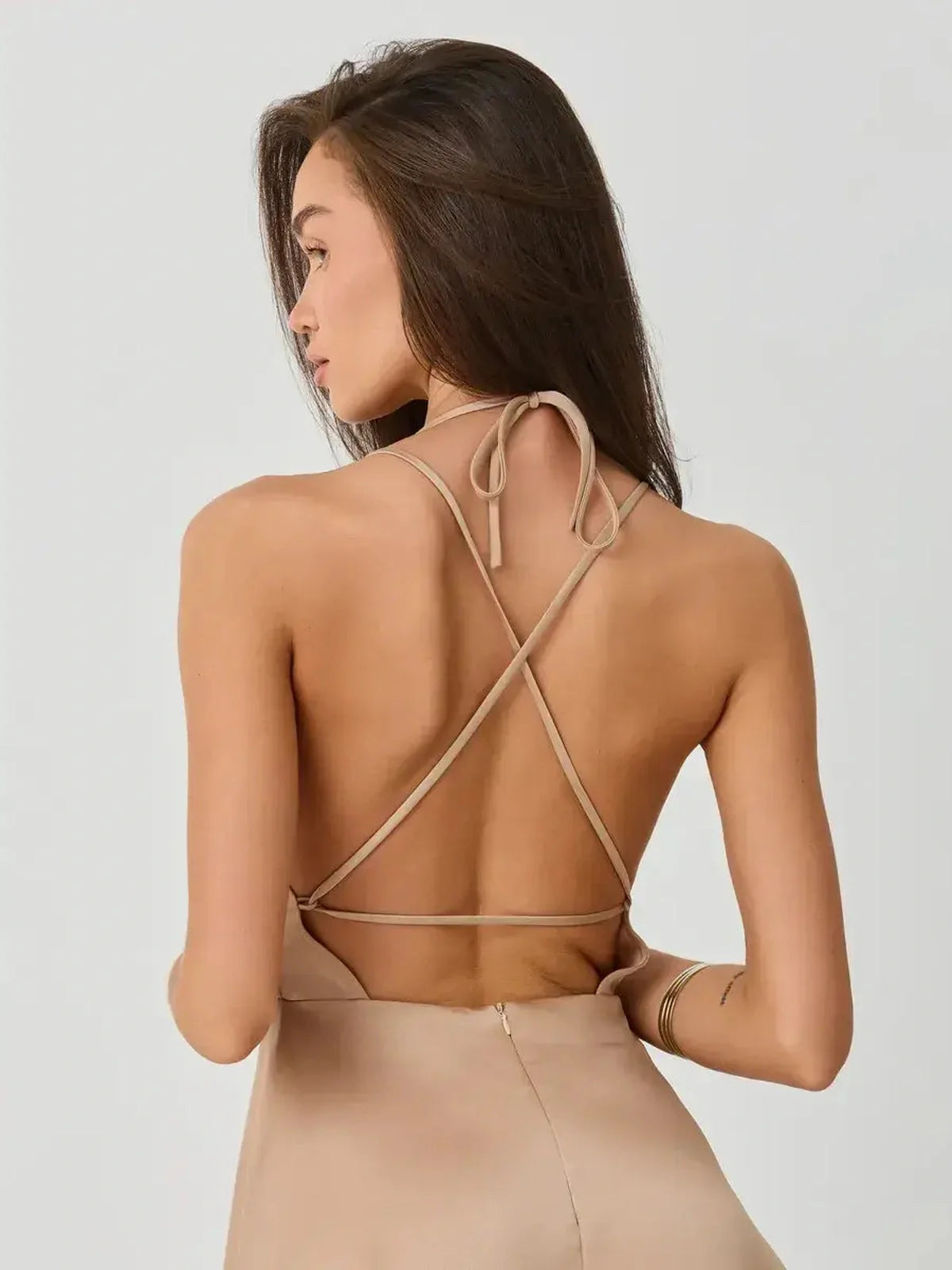 Back view of a woman in a Satin Whisper mini dress showcasing double spaghetti straps and a stylish open back.