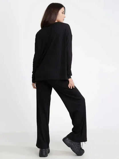 Model showcases the Jet Black Set, featuring a relaxed ribbed two-piece with loose-fit long sleeves and wide-leg pants.
