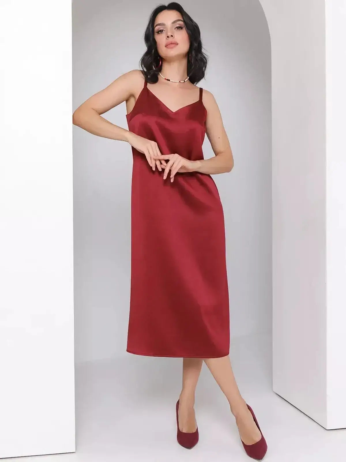 Model wearing a burgundy Satin Charm Midi Dress featuring adjustable straps and a fluid silhouette, perfect for weddings or formal events.