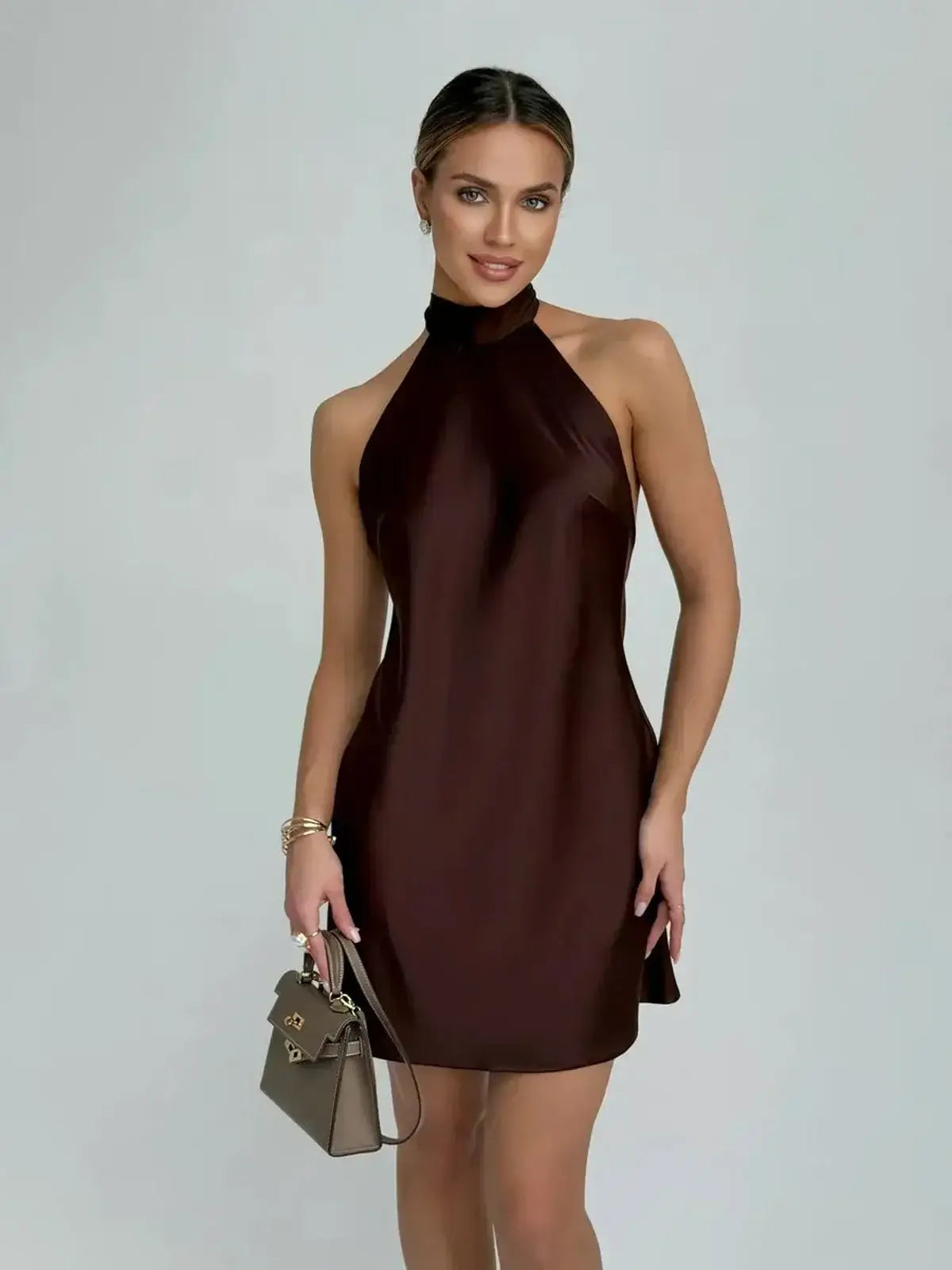 Model wearing a Mocha Silk Mini dress showcasing a sleek halter neckline and open back, perfect for cocktail events.