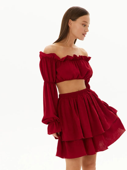 Model showcasing a red ruffle summer set featuring an off-shoulder crop top and tiered mini skirt, perfect for warm-weather occasions.