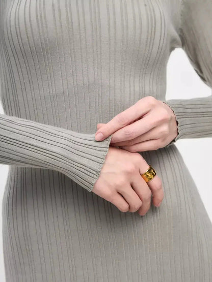 Close-up of a woman's hands wearing a ribbed maxi dress with long sleeves, showcasing elegant styling and detail.