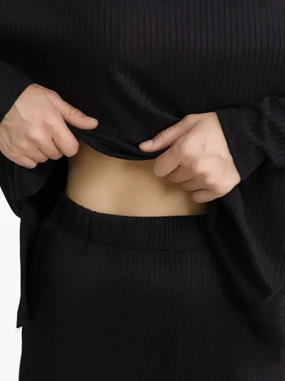 Close-up of a woman adjusting the ribbed top of a Jet Black Set, showcasing its relaxed silhouette and comfort.