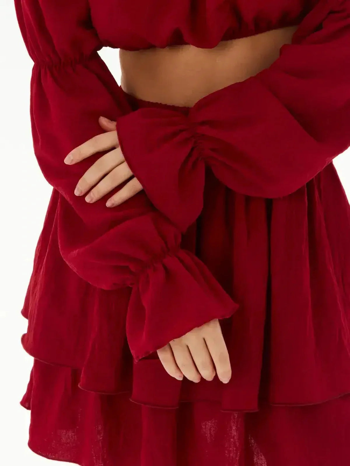 Close-up of a model's hands in a ruffle summer set featuring voluminous red sleeves and layered skirt.