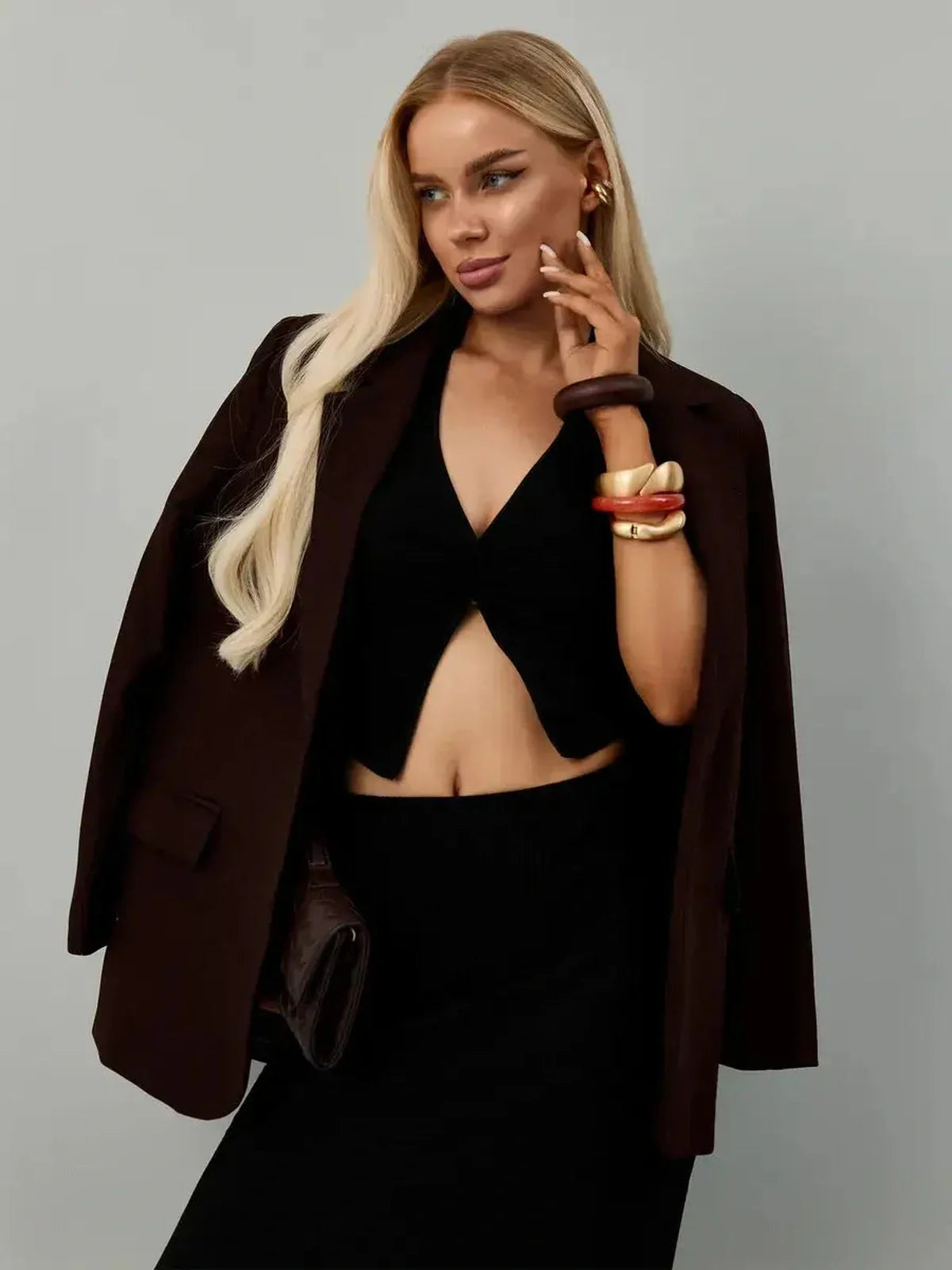 Chic woman modeling a Noir Edge Set featuring a halter top and maxi skirt, styled with a blazer and accessories.