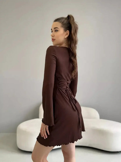 Woman in a brown mini dress with long bell sleeves and self-tie back, showcasing modern femininity.