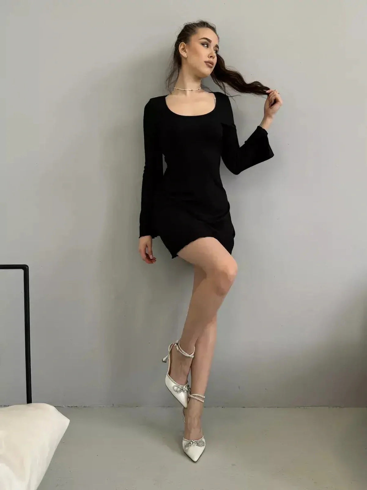 Model wearing a stylish mini black dress with flared sleeves, showcasing elegance and versatility for special occasions.