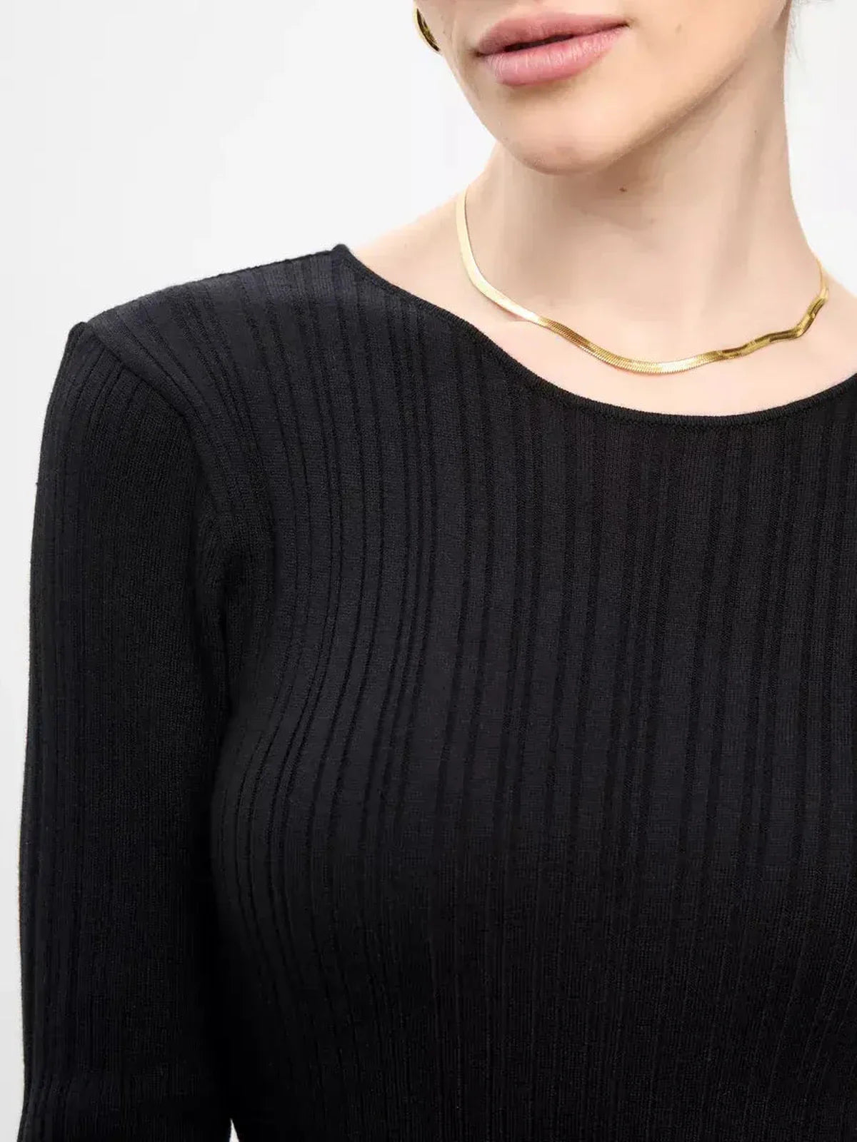 Close-up of a woman's elegant black ribbed dress top paired with a chic gold necklace.