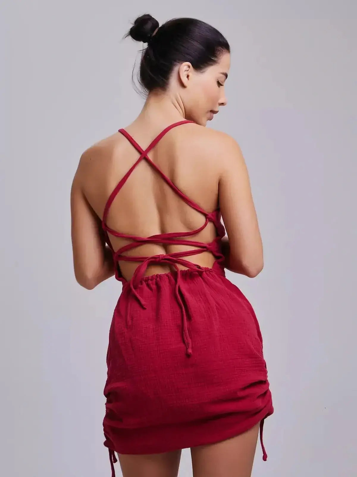 Back view of a woman wearing a fitted crimson mini dress with lace-up details, perfect for summer weddings and proms.