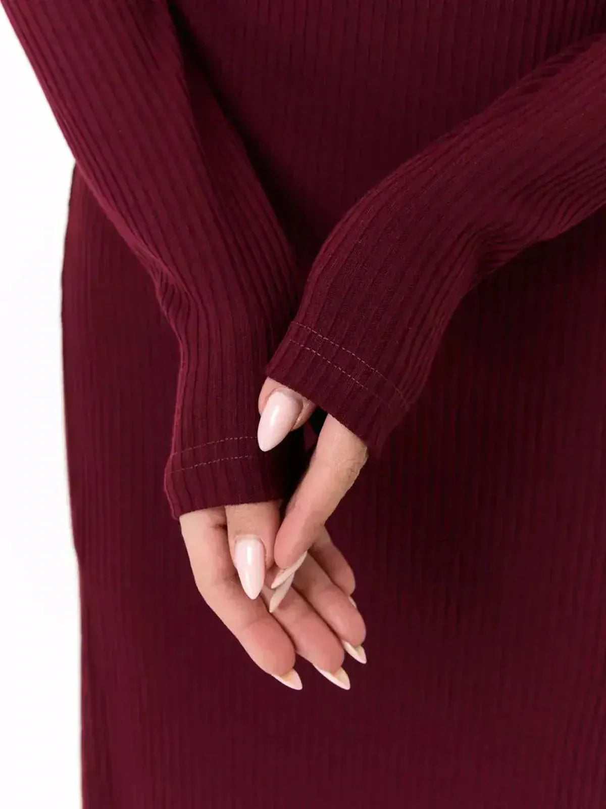 Close-up of hands in long sleeves of a burgundy velvet edge midi dress, showcasing ribbed texture and stylish design.