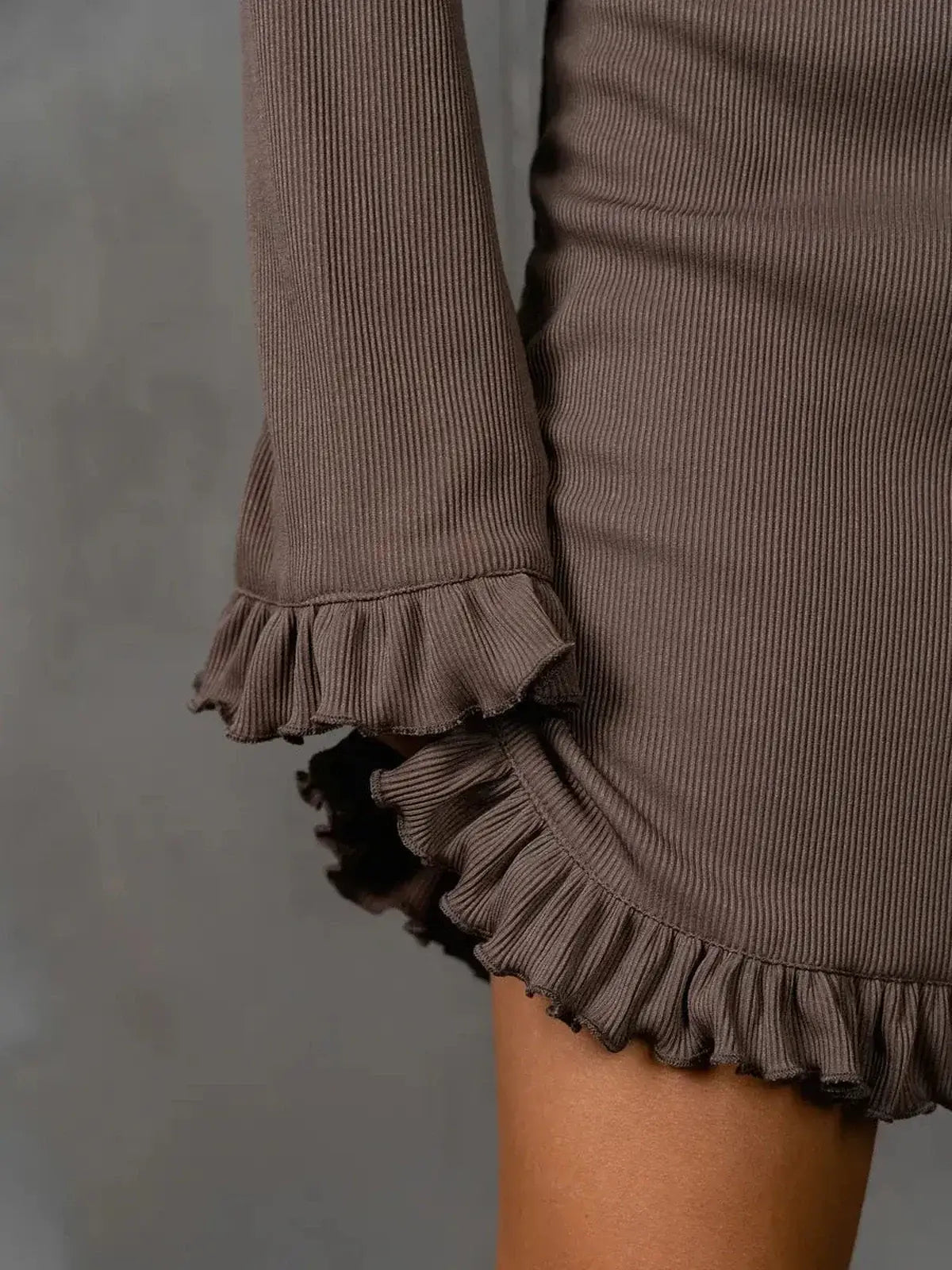 Close-up of Cocoa Flare dress showcasing ruffle trim on sleeves and hem, highlighting its elegant design.