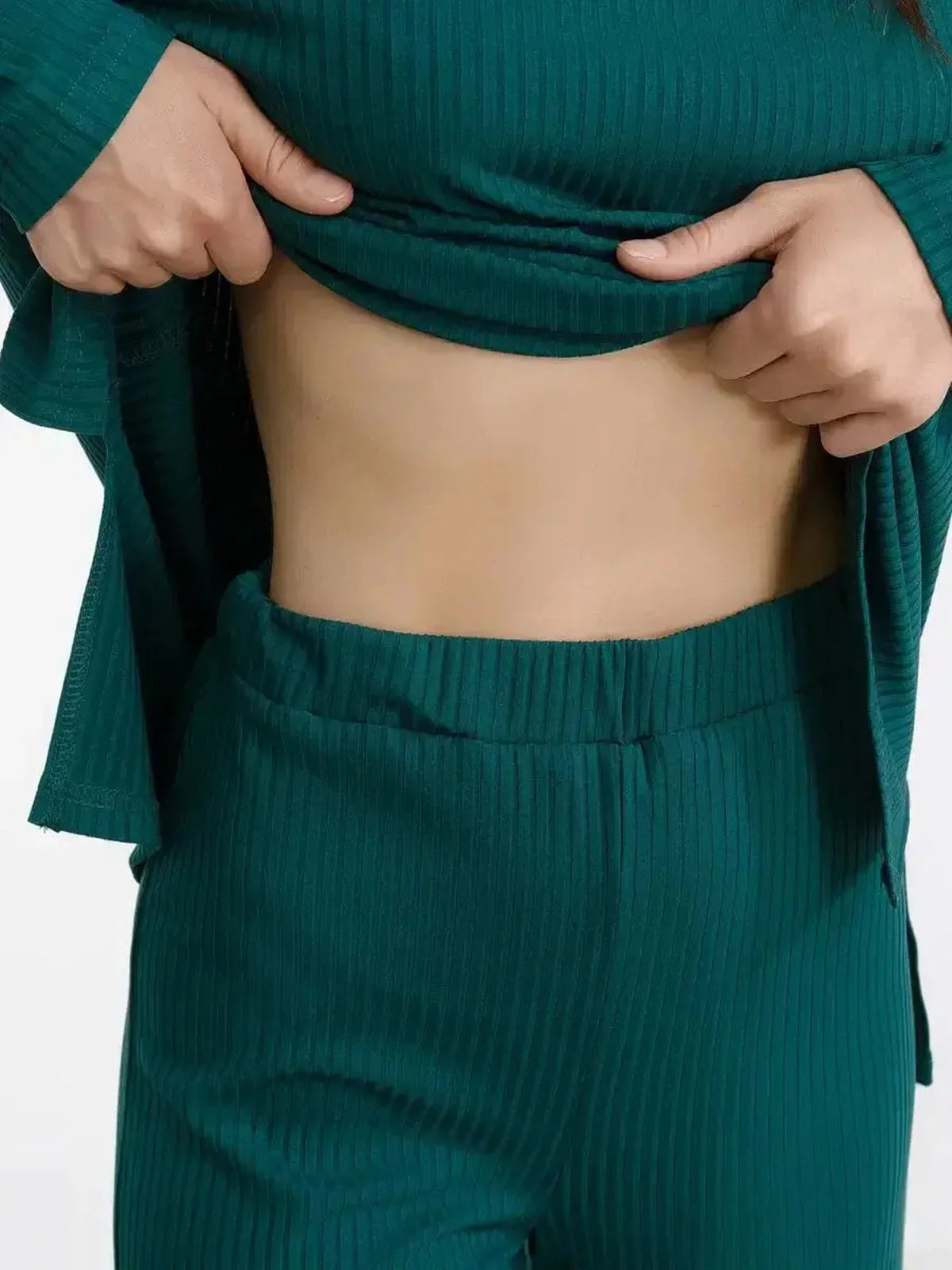 Close-up of a woman adjusting the ribbed dark green LoungeEase Set, showcasing its relaxed fit and comfort.