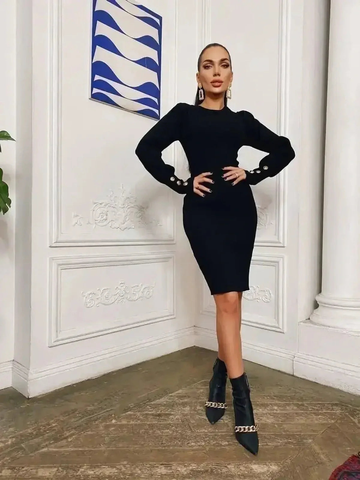 Stylish woman in a black mini dress with gathered shoulders and gold-tone buttons, perfect for formal events.