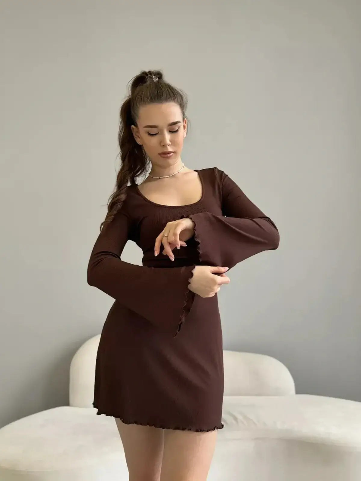Model showcasing the Mocha Muse mini dress featuring long sleeves and a scoop neckline, perfect for stylish outings.