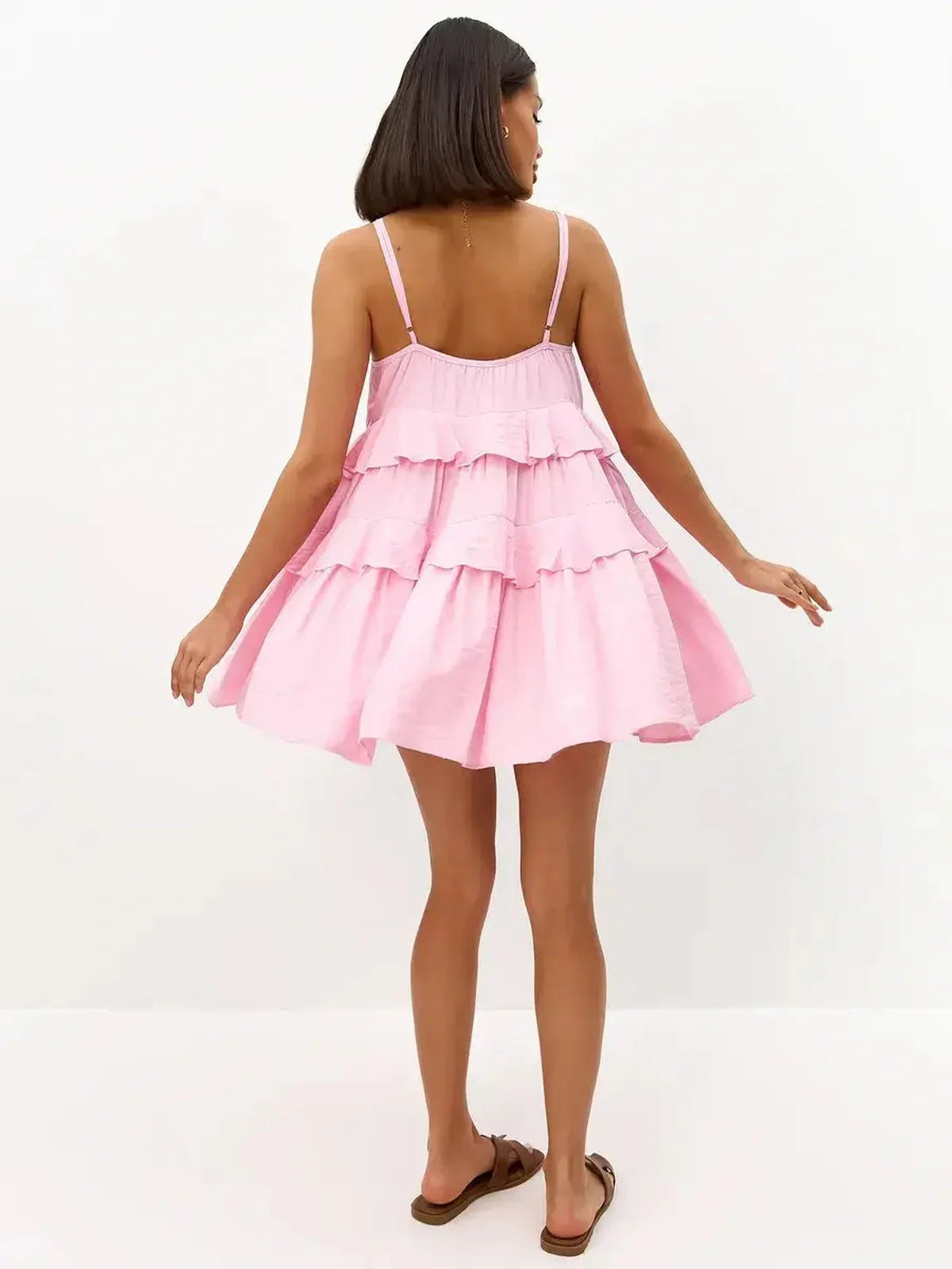 Back view of a woman in a pink mini dress with tiered ruffles, perfect for summer occasions and casual outings.
