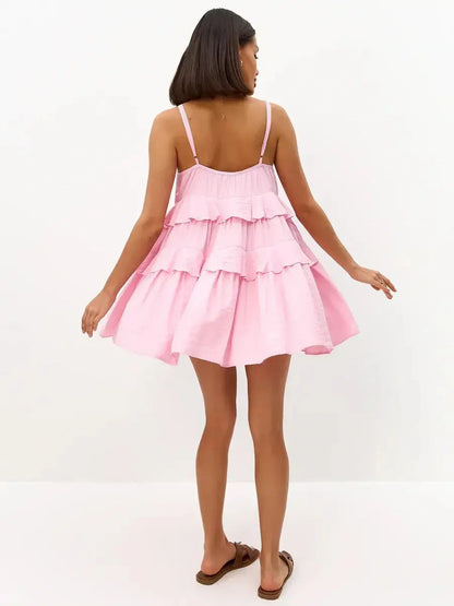 Back view of a woman in a pink mini dress with tiered ruffles, perfect for summer occasions and casual outings.