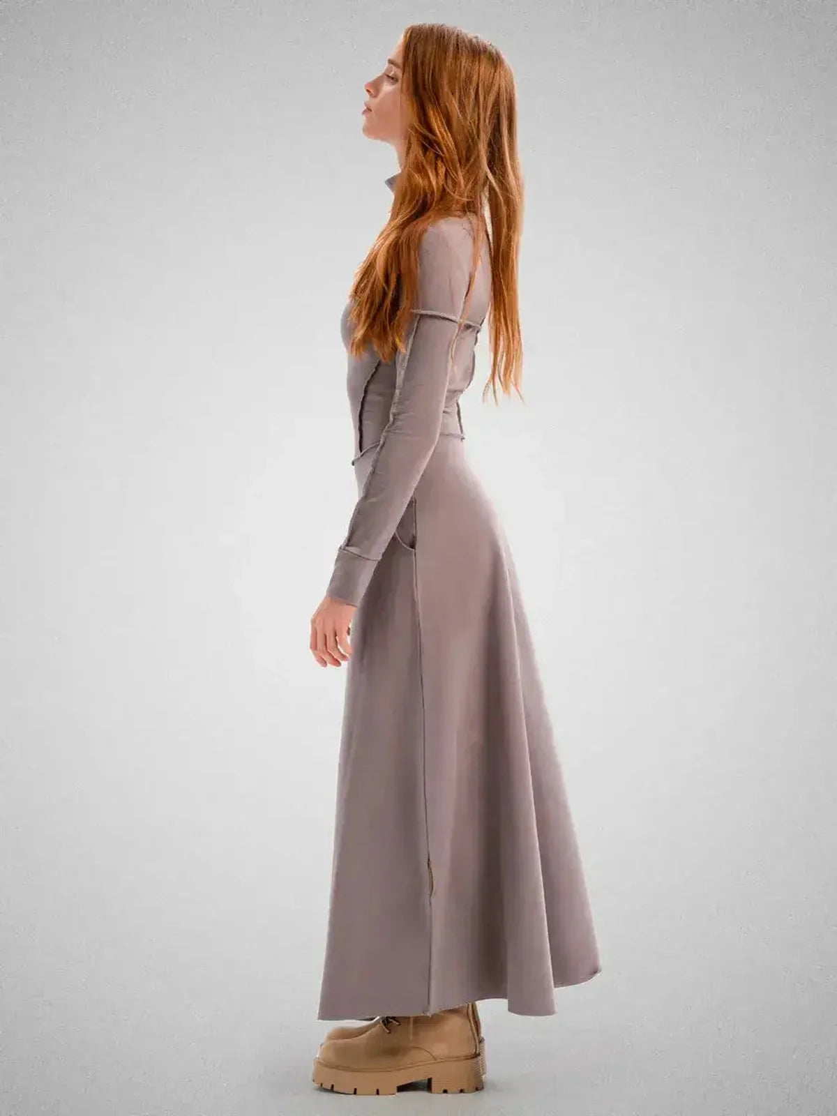 Side view of a woman wearing a sleek Maxi Dress Contour Grace in soft gray, showcasing its flowing silhouette and modern design.