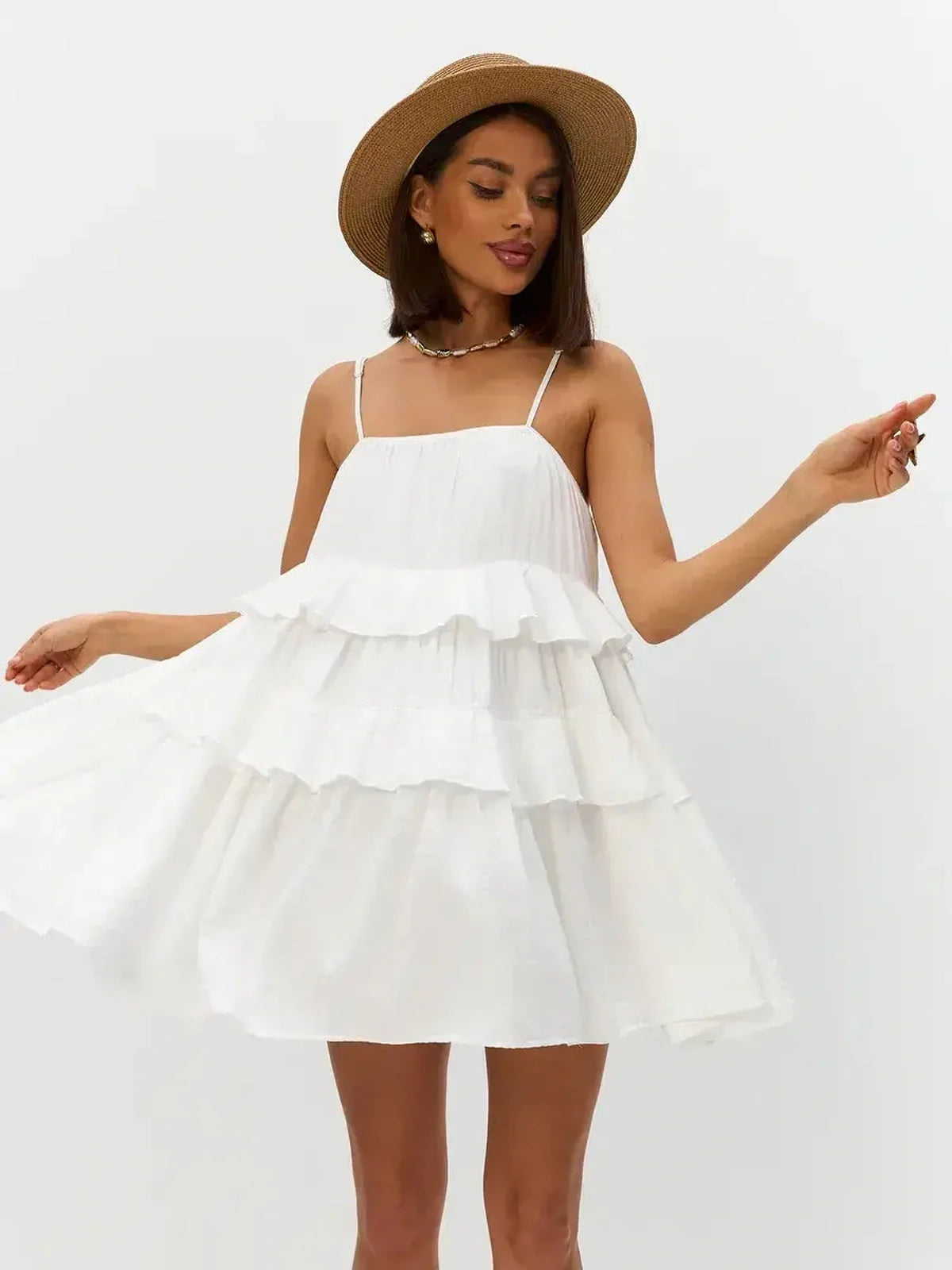 Model wearing the Riviera Ruffle white summer dress, featuring tiered ruffles and delicate shoulder straps.