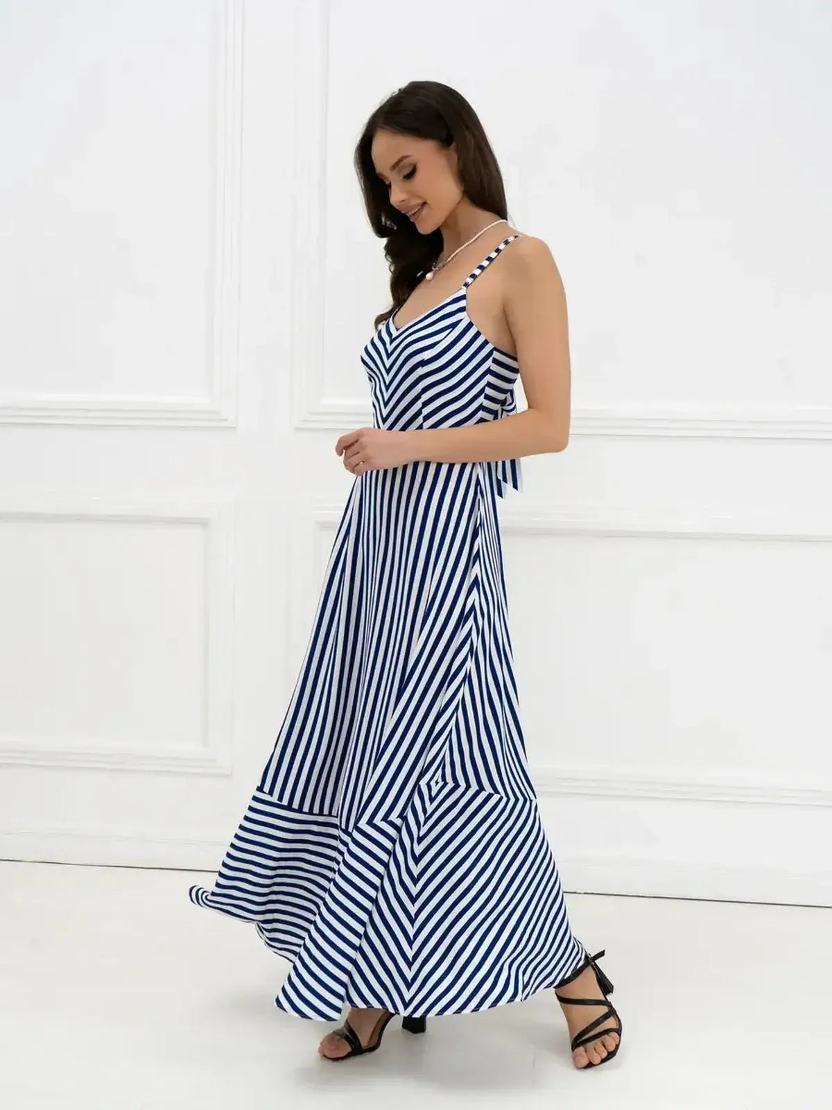 Elegant woman wearing the Marina Stripe Maxi Dress featuring a bold stripe pattern and flowing silhouette.