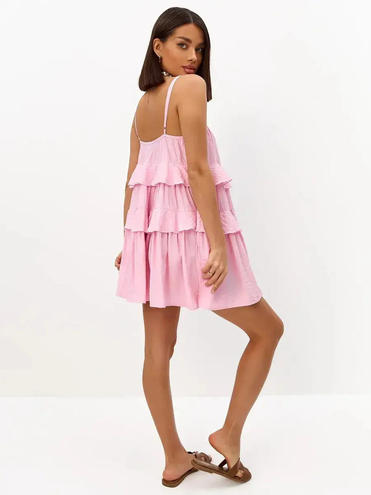 Playful pink mini dress with spaghetti straps and tiered ruffles, perfect for summer occasions.