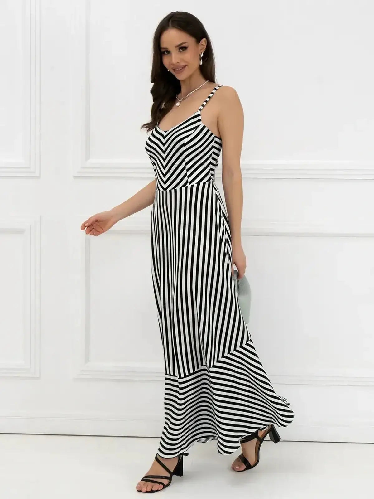 Elegant black and white striped maxi dress featuring a fitted bodice and A-line silhouette, ideal for weddings or summer outings.