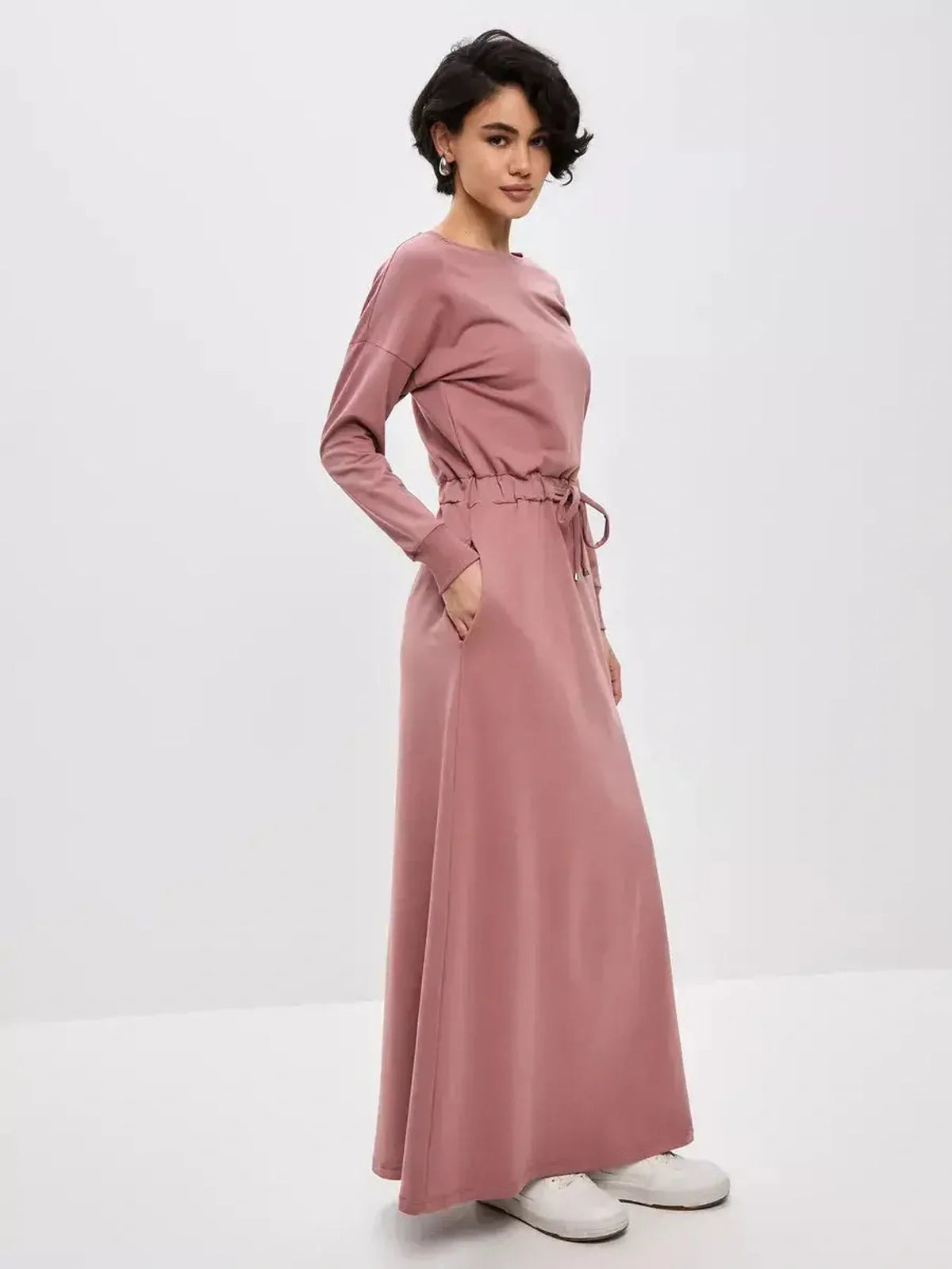 Woman wearing a blush lounge maxi dress featuring a drawstring waist in a soft, dusty pink hue, ideal for casual elegance.