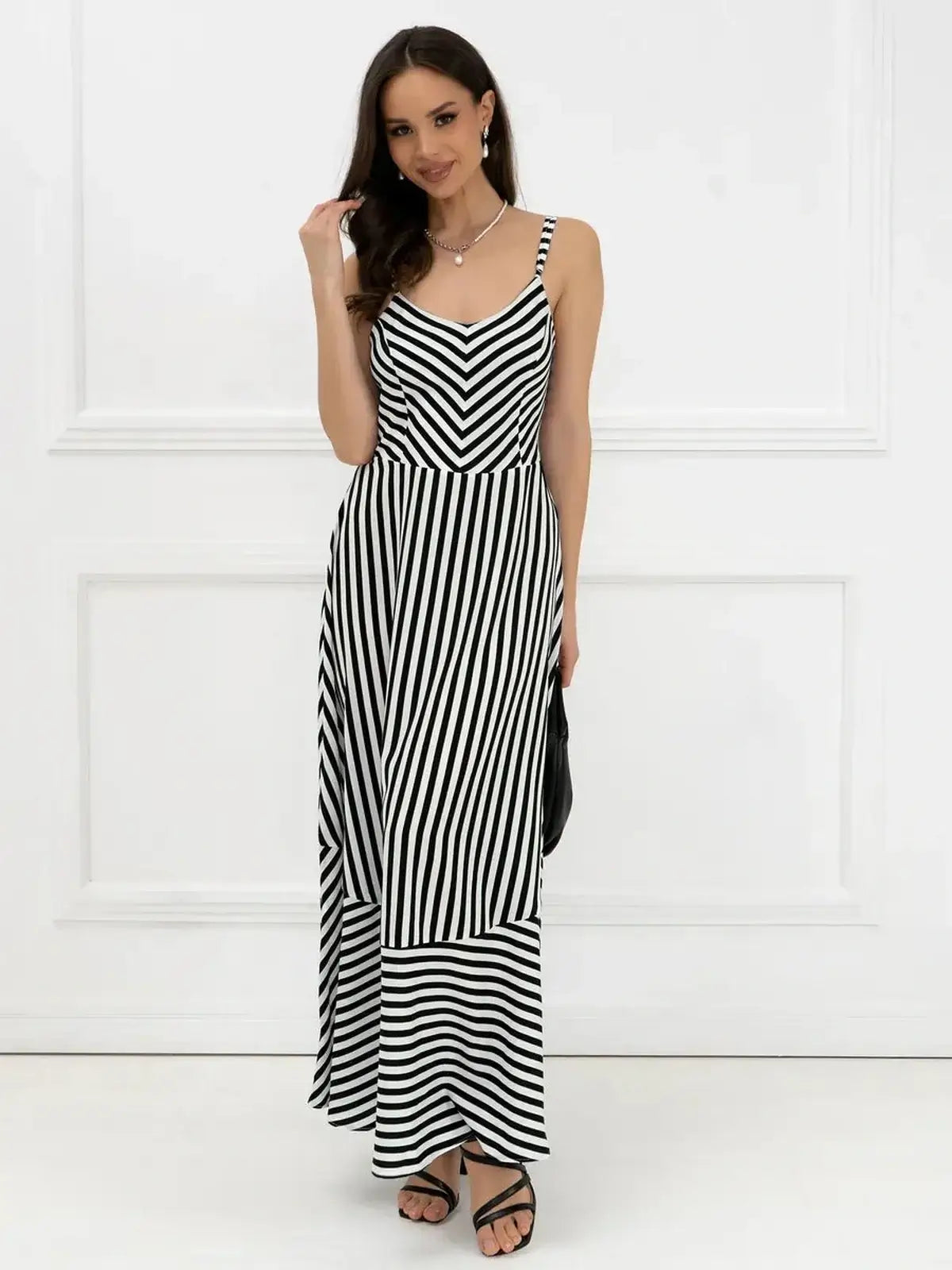 Woman in a black and white striped maxi dress with a fitted bodice, perfect for weddings and summer occasions.