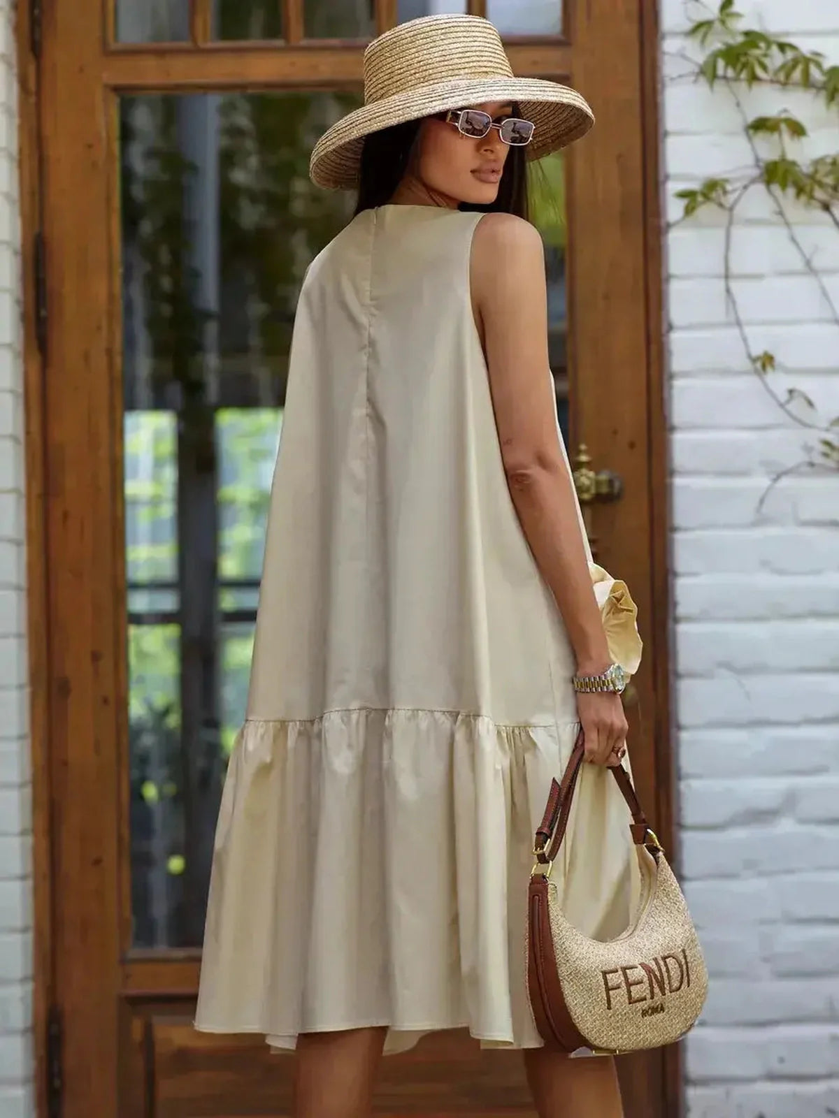 Charming midi dress in champagne, featuring a wide-tiered hem and summer accessories for warm-weather events.