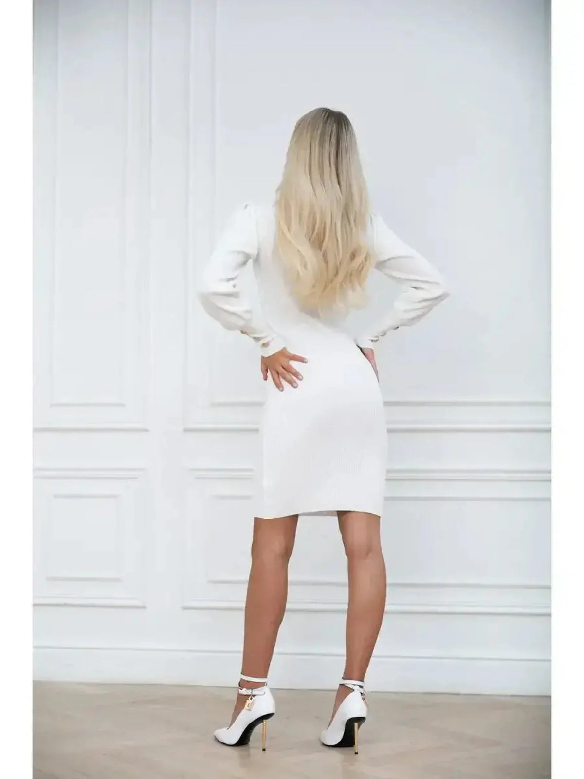 Elegant white mini dress with elegant long sleeves, showcasing a fitted silhouette and chic high heels from the back.