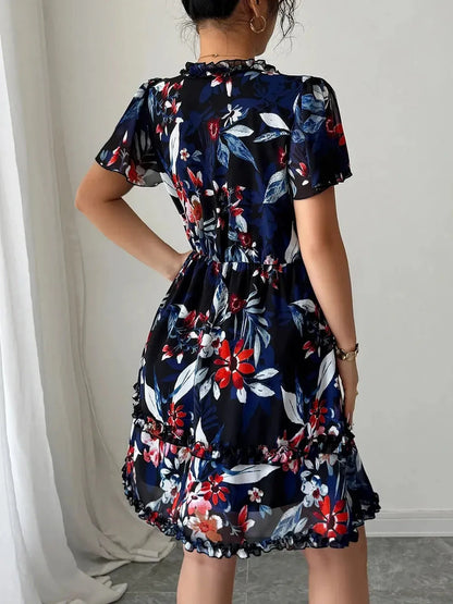 Back view of a floral mini dress in navy blue with vibrant red and white flowers, showcasing soft ruffles and an elastic waist.