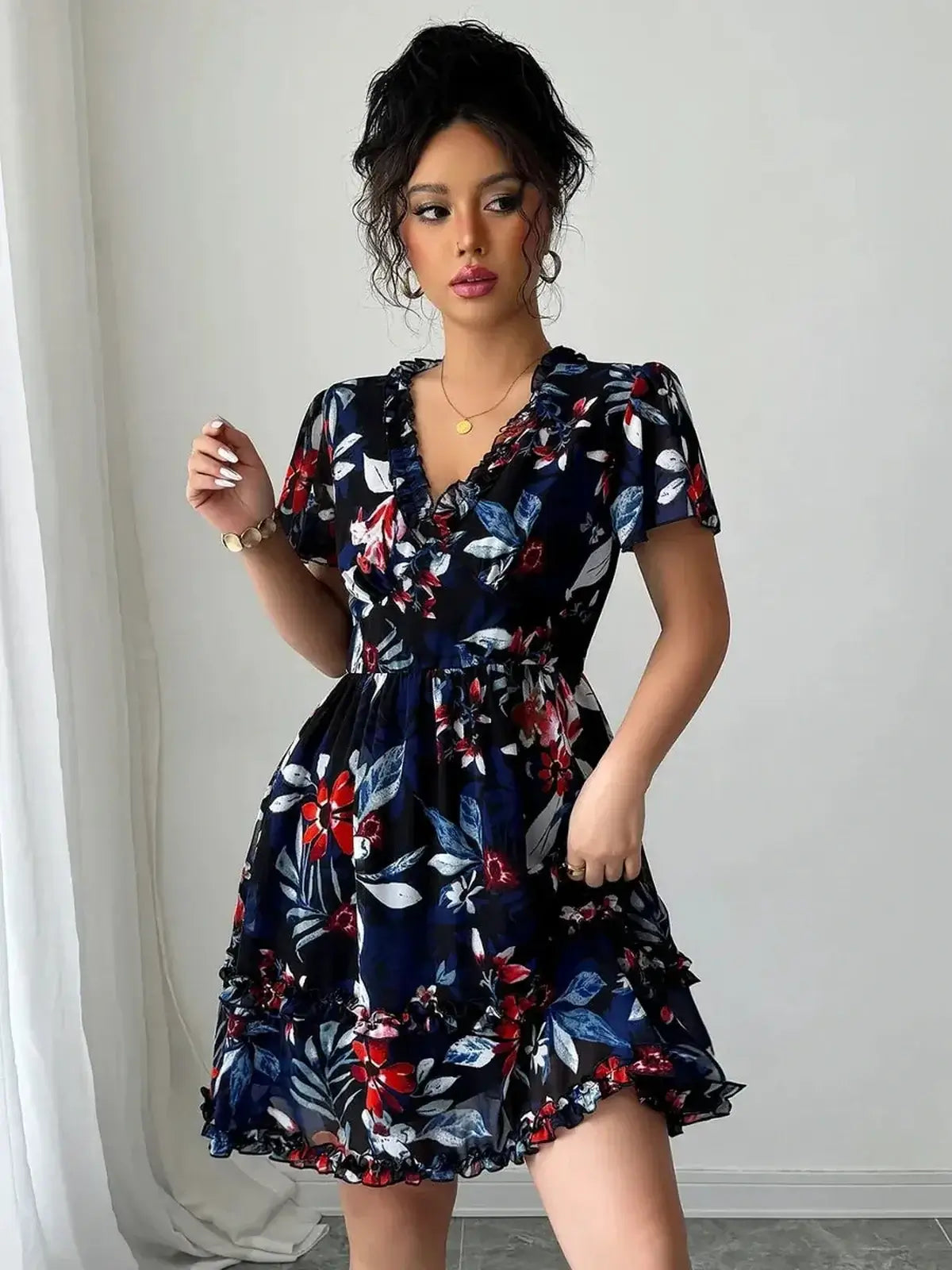 Floral mini dress in rich black base with vibrant flowers, featuring short ruffled sleeves and deep V-neckline.