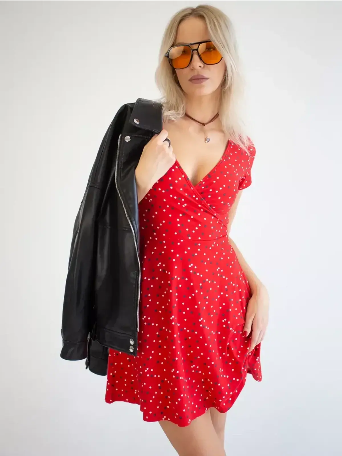 Model wearing a red polka dot mini dress with a leather jacket, ideal for summer parties and weddings.