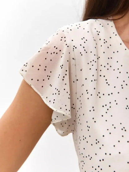 Close-up of flutter sleeves on the Ivory Glimmer mini dress featuring a chic polka dot print.