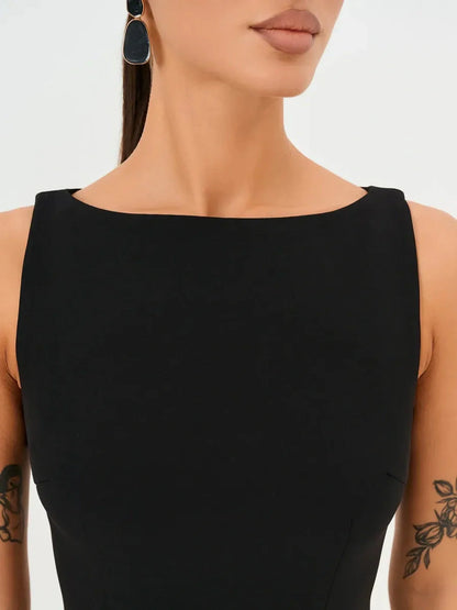 Close-up of a woman in a sleeveless black mini dress with a round neckline and elegant earrings.
