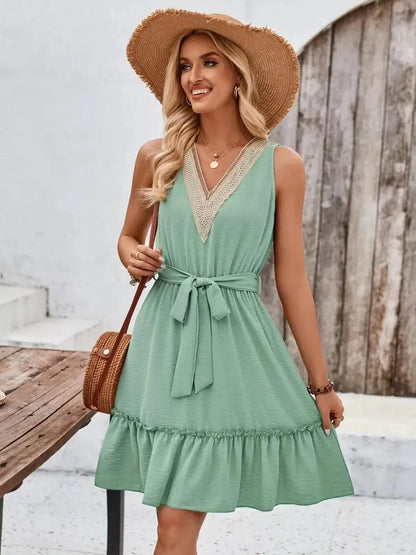Woman wearing a mint green Lace Breeze Mini Dress with a V-neckline and flared hem, perfect for summer occasions.