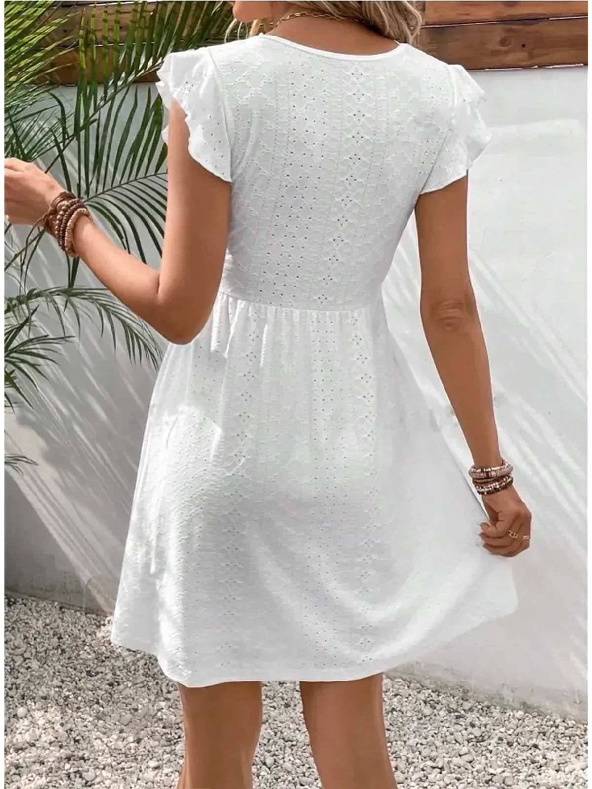 Back view of a stylish white Lace Halo Mini Dress with flutter sleeves, perfect for summer and wedding guest outfits.