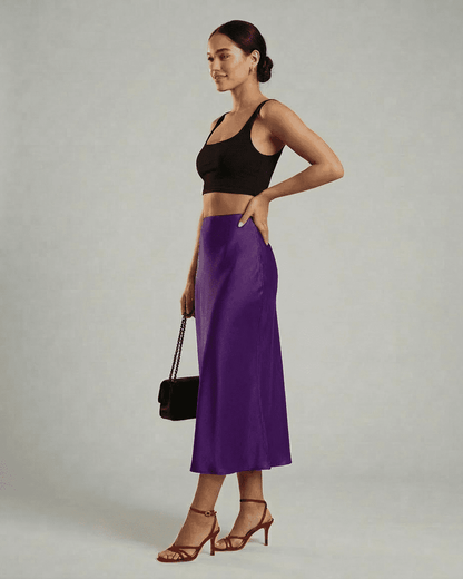 Model showcasing Slimona Amethyst Midi Skirt in vibrant purple, paired with a black crop top and red heels.