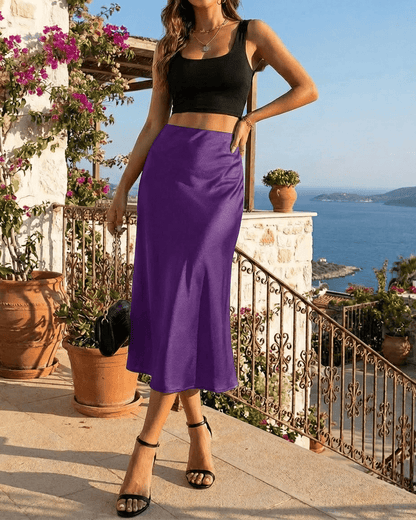 Model showcases the Amethyst Midi Skirt by Slimona, featuring a vibrant purple satin design in an elegant setting.
