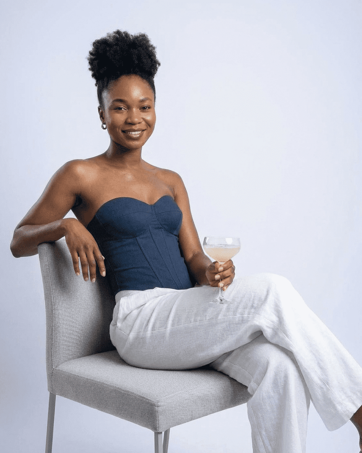 Model wearing Atlas Corset Top by Slimona, a navy faux denim cup bustier styled with elegant white pants.