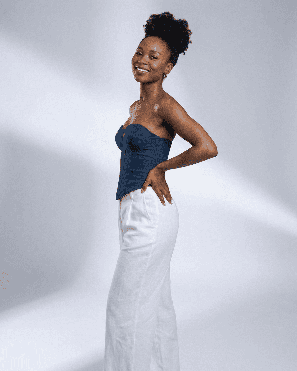 Woman wearing Slimona Atlas Corset Top in faux denim, styled with white wide-leg pants against a light backdrop.