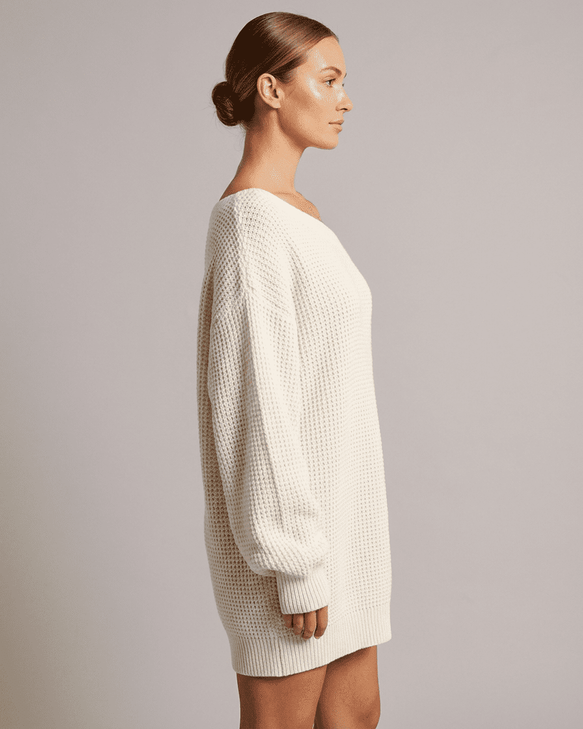 Side view of a woman wearing the Slimona Aurora Mini Dress, featuring a cozy white ribbed knit design.