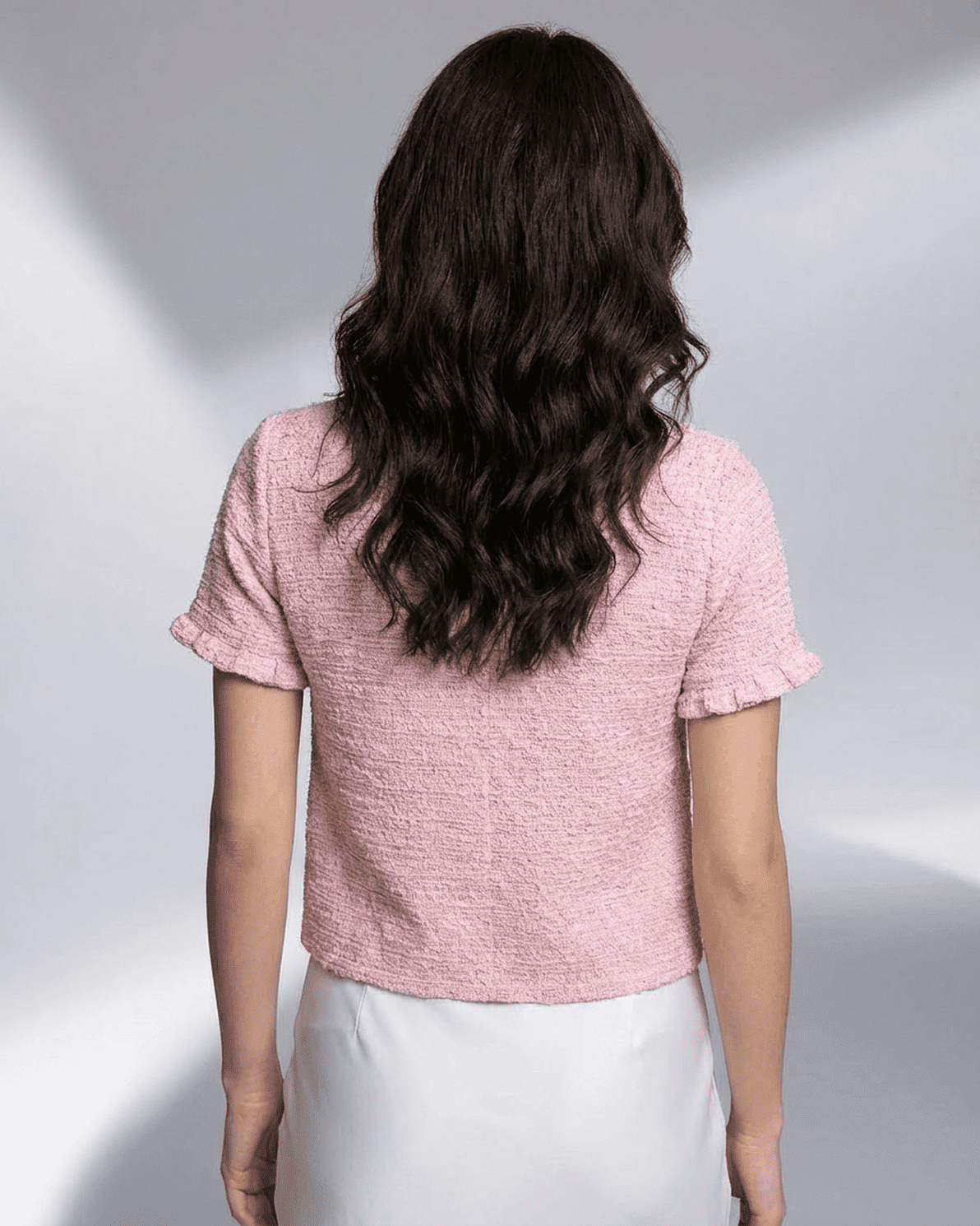 Back view of a woman wearing a pink Camellia Cardigan from Slimona, showcasing its short sleeves and stylish design.