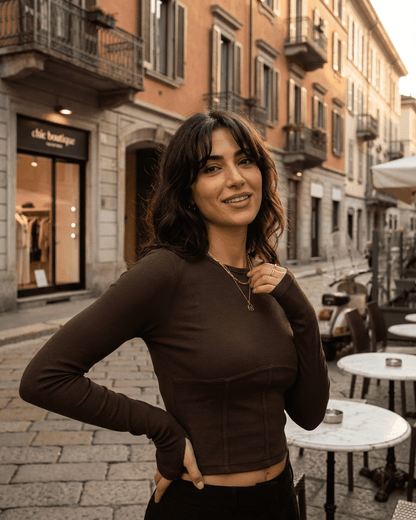 Woman wearing the Cocoa Corset Top by Slimona, showcasing a stylish long sleeve jersey crop in an urban setting.