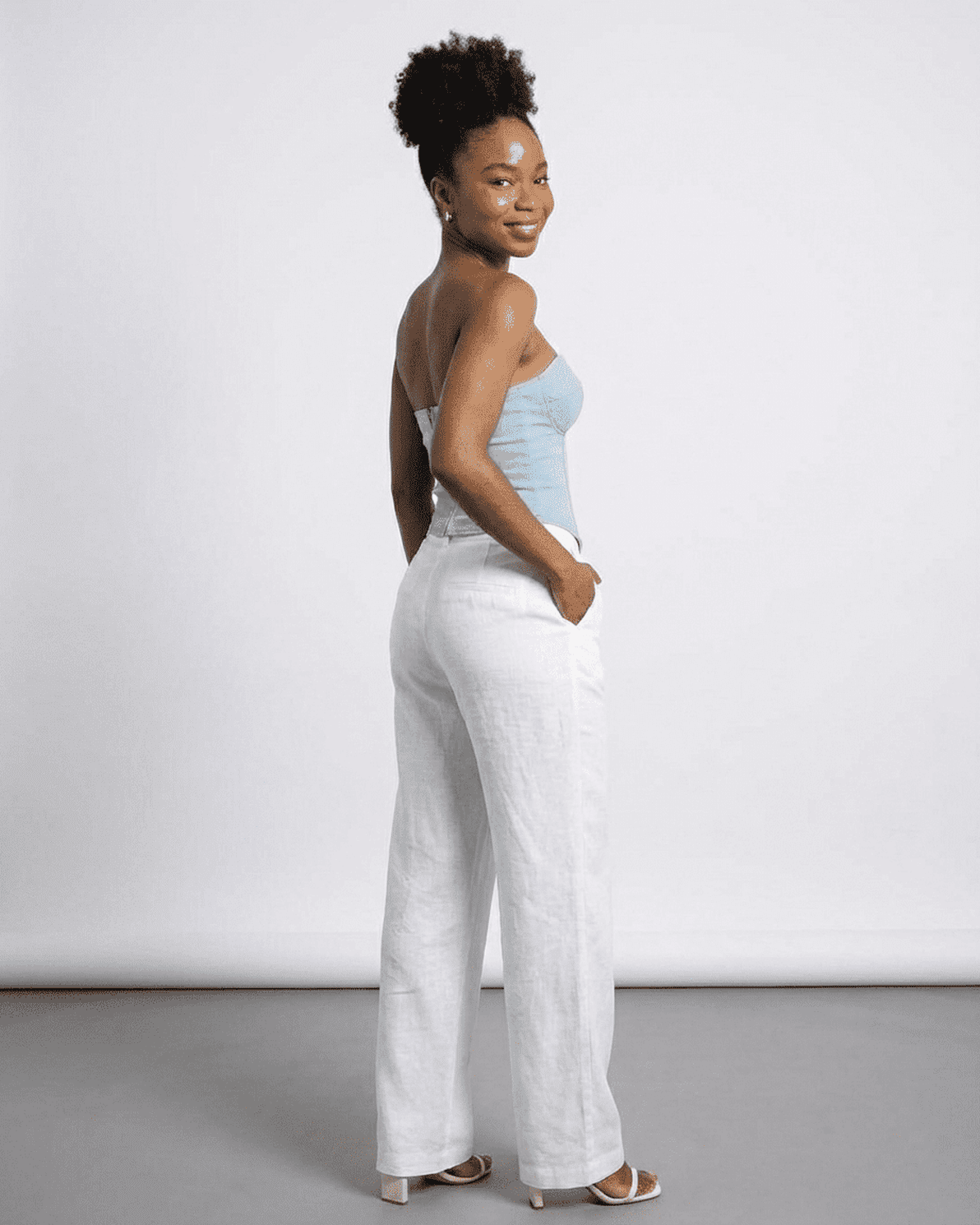 Denali Corset Top by Slimona, showcasing a woman in a faux denim bustier with stylish white linen pants.