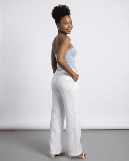 Denali Corset Top by Slimona, showcasing a woman in a faux denim bustier with stylish white linen pants.