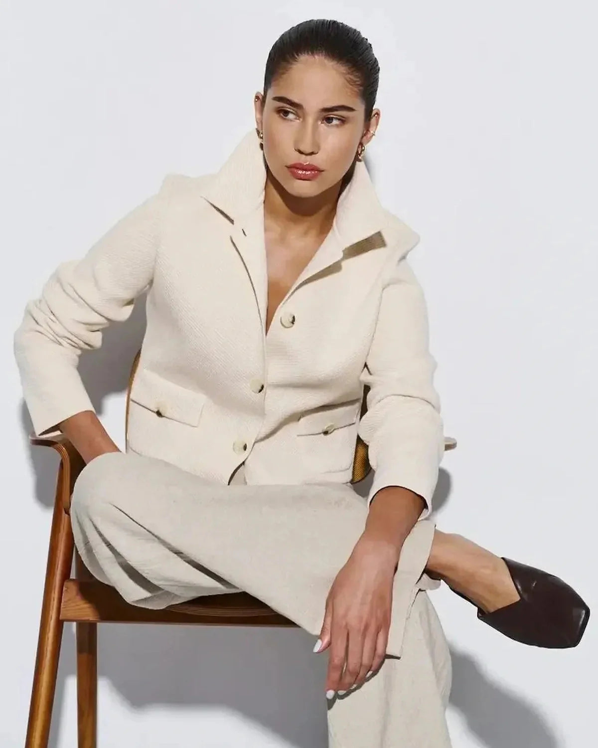 Elegant woman wearing Lazio Cropped Jacket by Slimona, showcasing chic cream color and tailored silhouette.