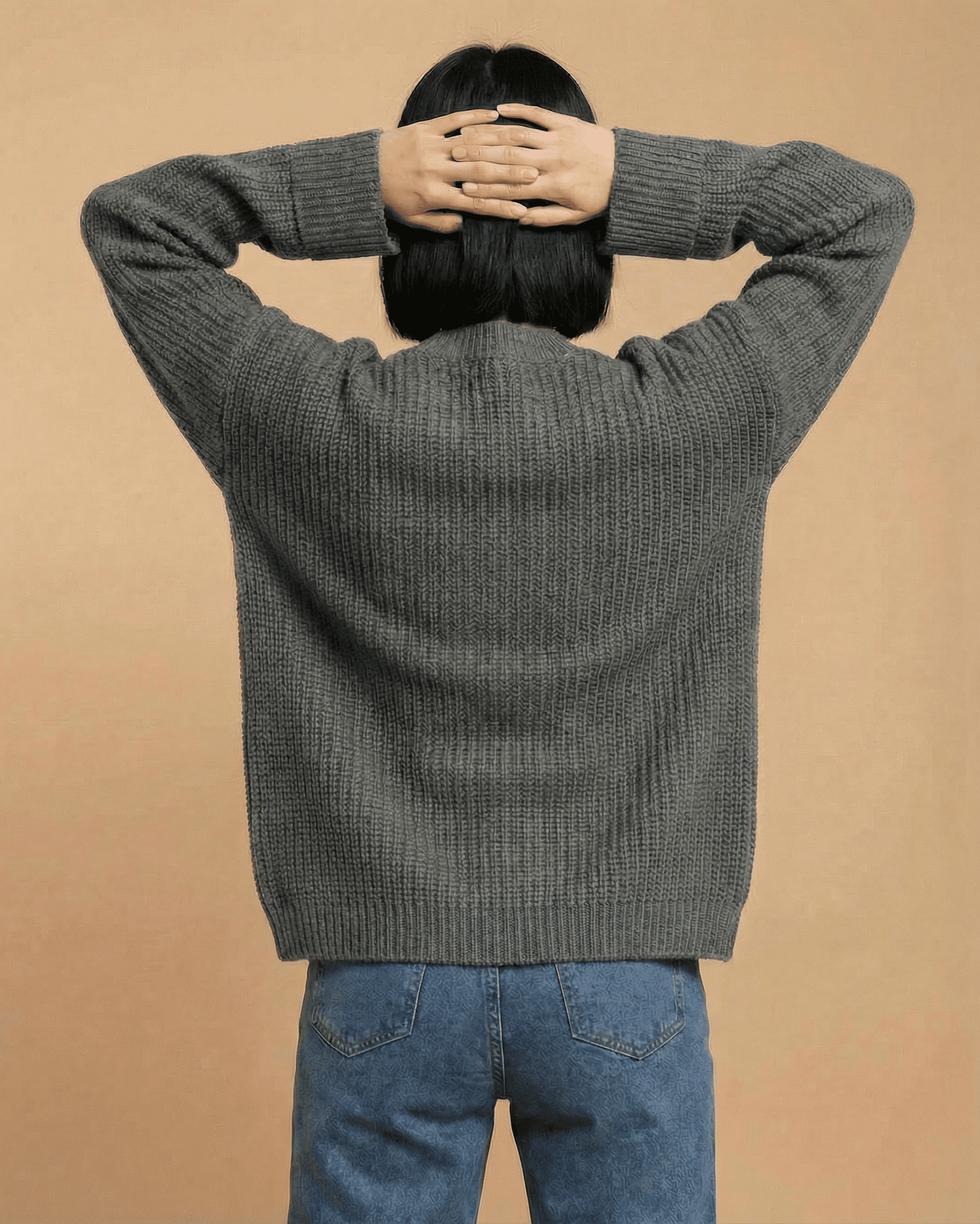 Back view of a woman wearing a relaxed fit gray Linden Cardigan from Slimona, showcasing its cozy knit design.